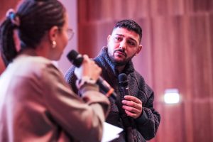 Auf dem Bild ist eine Frau von hinten mit einem Mikro und ein Mann von vorne mit einem Mikro zu sehen