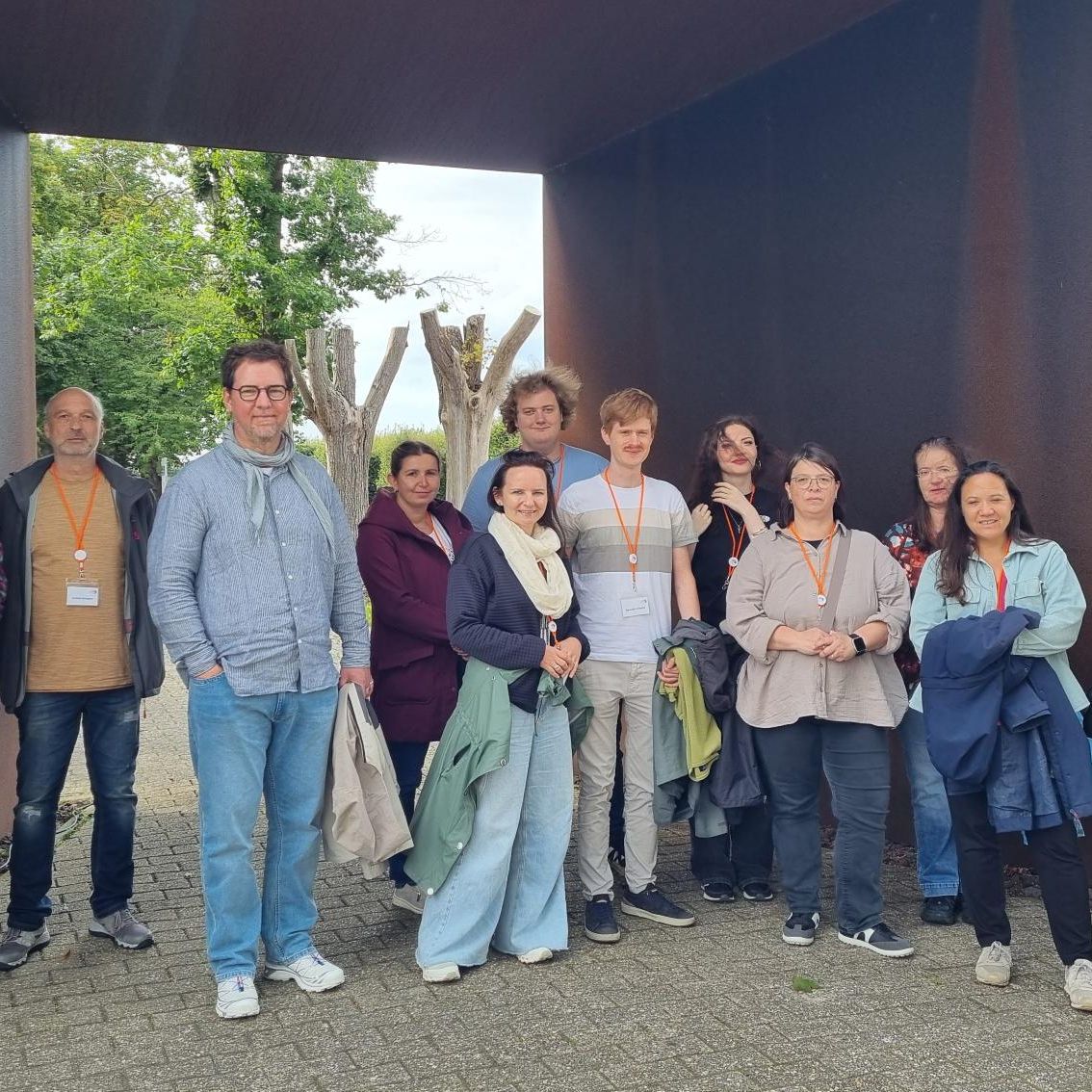 Auf diesem Bild sieht man eine Gruppe von Menschen unter einer verrosteten Eisenbrücke stehen